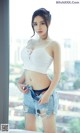 A woman in a white top and denim shorts posing for a picture.