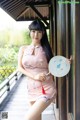 A woman in a pink dress holding a fan.