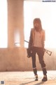 A woman in a white shirt and black pants holding a gun.