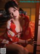 A woman in a red kimono sitting on a bed.