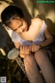 A woman sitting on a bench holding a shower head.