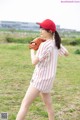 A woman in a baseball uniform holding a baseball glove.