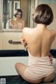 A woman sitting in a bathtub looking at herself in the mirror.