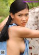 A woman with long black hair leaning against a wall.