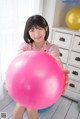 A young woman holding a large pink ball in her hands.