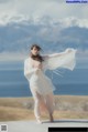 A woman in a white dress standing on a wooden platform.