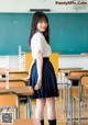 A woman in a school uniform standing in front of a blackboard.