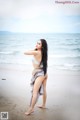 A woman standing on a beach next to the ocean.