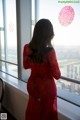 A woman in a red dress looking out a window.