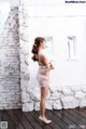 A woman standing in front of a white brick wall.